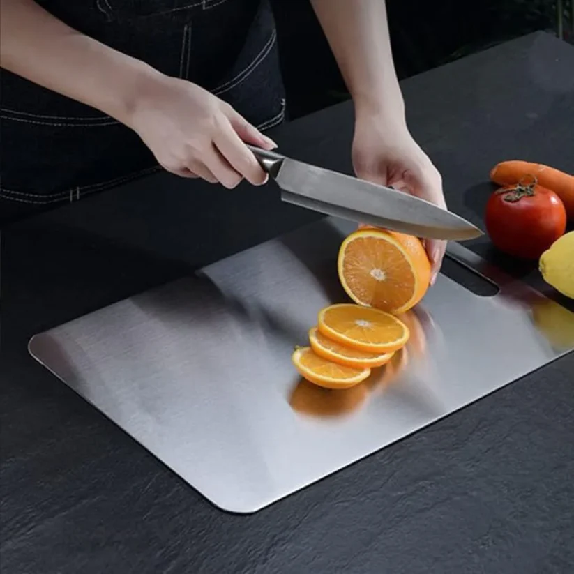 Orangen werden mit einem Kochmesser auf dem antibakteriellen Titan-Schneidebrett geschnitten